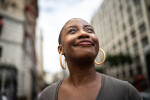 African American woman smiling and looking up in a city setting